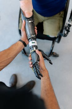 Close-up of a man in a wheelchair with a prosthetic hand offering a handshake.