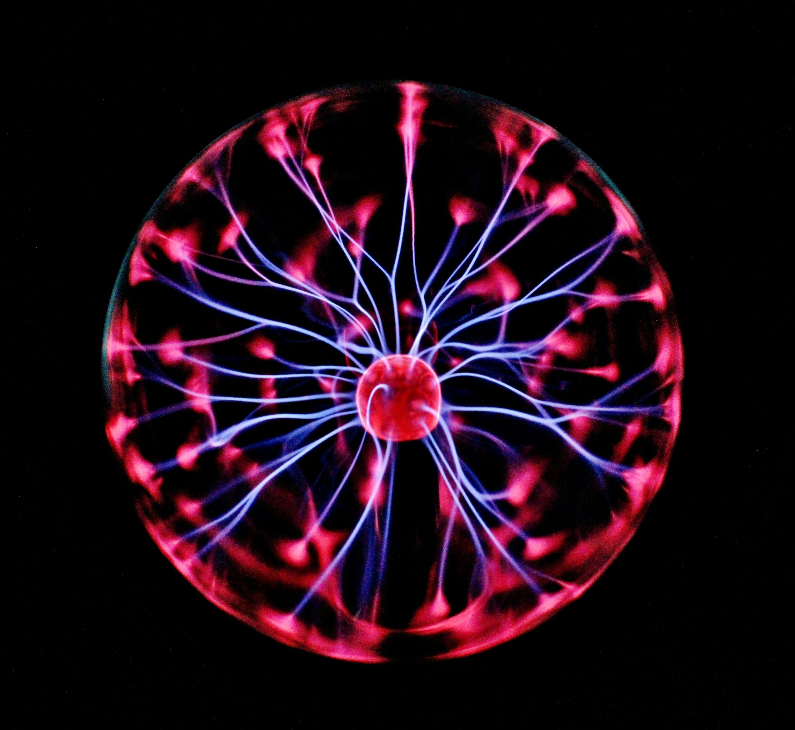 Close-up of a plasma globe with vibrant neon sparks against a dark background.