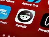 Detailed view of the Reddit app icon on a smartphone screen displaying popular applications.