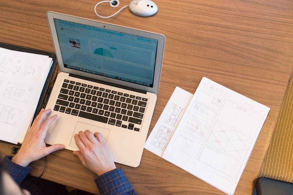 An overhead view of a person working on a laptop at a desk with documents and papers.