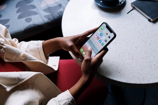 A person checks social media apps on a smartphone while sitting at a café table.