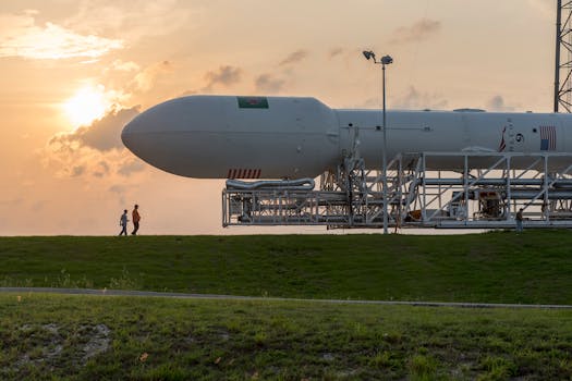 A space shuttle on a launchpad with people walking nearby at sunset.